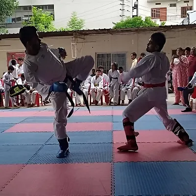 Two martial artists sparring during a match with spectators watching in the background