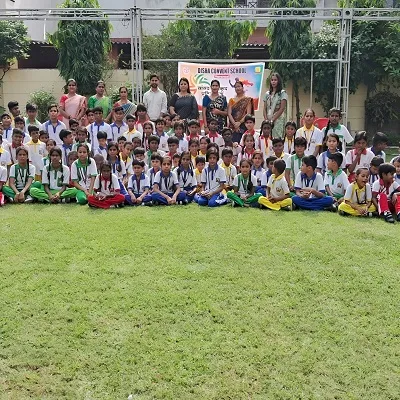 Group photo of school children in sports uniforms with medals and teachers standing behind
