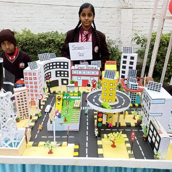 Schoolgirl presenting a detailed Smart City model with buildings, roads, and greenery at a school exhibition